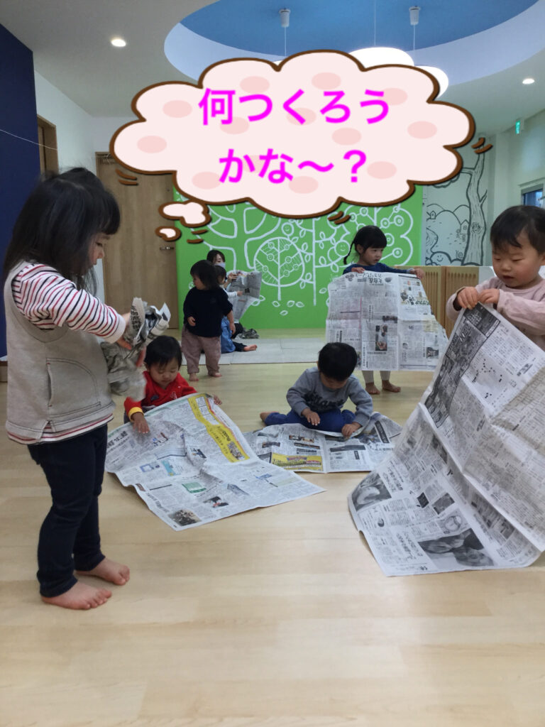 新聞紙をもって考えている園児たち